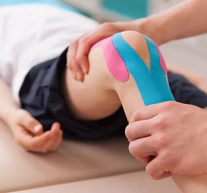 Image of an injured knee with kinesiology tape applied.